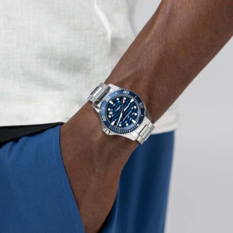 El Hamilton Khaki Navy Scuba Auto 40 mm H82425140 combina el espíritu aventurero de los relojes de buceo con un diseño contemporáneo pensado para acompañarte tanto dentro como fuera del agua. Esta nueva versión aporta una identidad más audaz a la colección gracias a su llamativa esfera azul lacada con textura ondulada, inspirada en el movimiento del océano, y a la renovada tipografía del bisel, que refuerza su carácter deportivo y moderno. Su caja de acero inoxidable de 40 mm ofrece un equilibrio perfecto entre presencia y comodidad, mientras que el cristal de zafiro con tratamiento antirreflejos garantiza una excelente resistencia y legibilidad. El robusto brazalete de acero inoxidable completa un conjunto versátil y elegante, ideal para el uso diario. Diseñado con el ADN de un auténtico reloj de buceo, incorpora bisel giratorio unidireccional de 60 minutos, corona roscada y una resistencia al agua de 100 metros (10 bares), características que aseguran fiabilidad y funcionalidad en cualquier entorno. En su interior late el calibre automático Hamilton H-10, un movimiento de alta precisión que ofrece una impresionante reserva de marcha de hasta 80 horas. Además, incorpora espiral Nivachron™, que mejora la resistencia a los campos magnéticos y contribuye a una mayor estabilidad y precisión del movimiento. Las agujas e índices con Super-LumiNova® garantizan una excelente visibilidad en condiciones de poca luz, reforzando su carácter deportivo y funcional. El Hamilton Khaki Navy Scuba Auto 40 mm es un reloj que une precisión suiza, resistencia y diseño contemporáneo, manteniendo vivo el legado de aventura y exploración que ha definido a Hamilton a lo largo de décadas de tradición en el mundo del buceo. Referencia Hamilton: H82425140 Referencia interna: R-HAM-KHA-0003