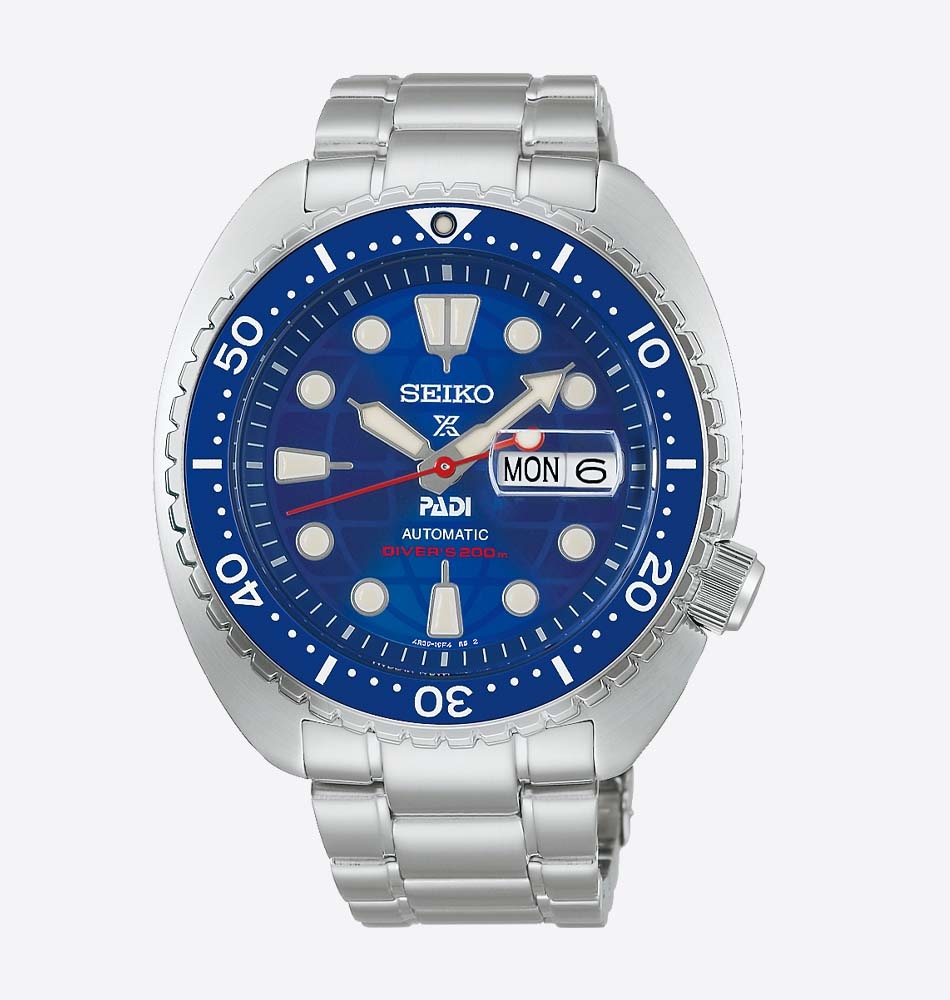 El Seiko Prospex Diver's Watch PADI 60th Anniversary Limited Edition SRPL53K1 (HBB002) celebra el 60.º aniversario de PADI y una década de colaboración entre ambas entidades, unidas por su compromiso con la seguridad en el buceo y la conservación de los océanos. Esta edición limitada a 8.000 unidades destaca por un diseño exclusivo inspirado en los colores del logotipo conmemorativo de PADI. Su llamativa esfera azul incorpora un sutil motivo de globo terráqueo, detalles en rojo en la aguja de los segundos y en el índice de las 6 horas, mientras que el bisel unidireccional con inserto de cerámica aporta una gran resistencia a los arañazos. La caja de acero inoxidable de 45 mm se complementa con un cristal de zafiro con lupa y tratamiento antirreflectante, así como con LumiBrite en agujas, índices y bisel para garantizar una excelente legibilidad bajo el agua. En su interior equipa el calibre automático 4R36, con capacidad de carga manual, 41 horas de reserva de marcha e indicación de día y fecha. Además del brazalete de acero inoxidable, esta edición especial incluye una correa adicional de silicona con diseño de acordeón, ideal para llevar sobre un traje de neopreno. En resumen, este Seiko Prospex PADI 60th Anniversary Limited Edition combina exclusividad, fiabilidad y prestaciones profesionales en un reloj de buceo diseñado para los apasionados del mar y la relojería. Descubre toda nuestra colección de los relojes Seiko Prospex. Referencia SEIKO: HBB002K1 Referencia interna: R-SEI-PRO-0005