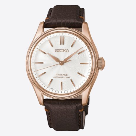 El Seiko Presage Classic Series HCC008 Tomioka Silk Promotion Organization Limited Edition es una edición limitada de 2.000 piezas inspirada en la exquisita belleza de la seda Tomioka, uno de los tejidos más prestigiosos de Japón. Esta creación rinde homenaje a la tradición sedera de la región de Gunma y a la histórica Tomioka Silk Mill, Patrimonio de la Humanidad, combinando artesanía japonesa y elegancia atemporal. Su refinada esfera presenta un delicado patrón que evoca la caída y la suave textura de la seda Tomioka. El sutil acabado nacarado refleja la luz con delicadeza, aportando una luminosa profundidad visual. La correa de piel marrón oscuro, inspirada en la emblemática fachada de ladrillo de la fábrica Tomioka Silk Mill, se armoniza con la caja de tono oro rosa, creando un conjunto sofisticado y distinguido. En su interior incorpora el calibre automático 6R51, con capacidad de carga manual y una reserva de marcha de hasta 72 horas, ofreciendo precisión y fiabilidad mecánica. La caja de 38 mm se completa con un cristal de zafiro de doble curvatura con tratamiento antirreflectante y un fondo transparente roscado que permite admirar el movimiento. Además, cuenta con una resistencia al agua de 10 bares (100 metros). Como parte de este proyecto especial, Seiko destina una parte de los ingresos a la Tomioka Silk Promotion Organization, contribuyendo a la preservación y difusión del legado cultural de la seda japonesa. Referencia Seiko: HCC008 Referencia interna: R-SEI-PRE-0014