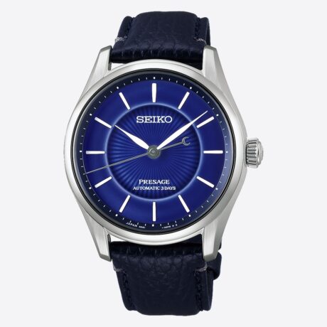 El Seiko Presage Classic Series HCC007 Seiko 145th Anniversary Limited Edition celebra el 145.º aniversario de Seiko con una creación excepcional limitada a 1.500 piezas. Este modelo destaca por su exclusiva esfera de porcelana Arita en azul cobalto, un tono inspirado en el emblemático Seiko Blue, símbolo de la identidad de la marca desde la década de 1960. La esfera, elaborada artesanalmente y cocida a alta temperatura, presenta un refinado patrón radial que realza la profundidad y las sutiles gradaciones del esmalte azul cobalto. Cada pieza es única, ya que las pequeñas variaciones propias de la porcelana Arita forman parte de su autenticidad y carácter artesanal. La nueva caja de la colección Presage Classic Series ha sido diseñada para potenciar la tridimensionalidad de la esfera, aportando una elegancia discreta y sofisticada. En su interior incorpora el calibre automático 6R51, con capacidad de carga manual y una reserva de marcha de hasta 72 horas, ofreciendo precisión y fiabilidad mecánica. La caja de 39,6 mm en acero inoxidable con revestimiento súper endurecido se combina con un cristal de zafiro de doble curvatura con tratamiento antirreflectante y una correa de piel de vaca procedente de curtidurías certificadas por el Leather Working Group, reflejando un compromiso con una producción más responsable. El reloj cuenta además con fondo transparente roscado, grabado “Limited Edition” y número de serie individual, subrayando su carácter exclusivo. En resumen, este Seiko Presage Classic Series Seiko 145th Anniversary Limited Edition une artesanía japonesa, precisión mecánica y diseño refinado en una pieza de colección que rinde homenaje a la historia y al legado de Seiko. Descubre toda nuestra colección de los relojes Seiko Presage. Referencia Seiko: HCC007J1 Referencia interna: R-SEI-PRE-0016
