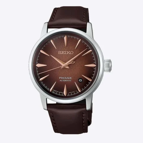 El Seiko Presage Cocktail Time Whiskey Mist HCB003J1 destaca por su elegante esfera en tonos ámbar, cobre y marrón, inspirada en la calidez y profundidad de los destilados envejecidos. Su acabado texturizado y sus reflejos cambiantes crean un atractivo efecto visual que aporta profundidad y personalidad al conjunto. La correa de piel de vacuno en marrón oscuro completa su estética clásica y refinada. En su interior incorpora el calibre automático 4R35, con capacidad de carga manual, una reserva de marcha aproximada de 41 horas y 23 rubíes. Además, cuenta con función de parada del segundero y visualización de la fecha, ofreciendo una lectura práctica para el día a día. La caja de acero inoxidable de 38,5 mm incorpora un cristal Hardlex en forma de caja y tratamiento antirreflectante. Las agujas e índices permiten una lectura clara, mientras que la correa de piel de vacuno marrón se integra con un cierre de tres pliegues con botón de apertura. El fondo de caja transparente y de rosca permite apreciar el movimiento mecánico en su interior. Con una resistencia al agua de 5 bares y resistencia magnética de 4.800 A/m, el Seiko Presage Cocktail Time Whiskey Mist HCB003J1 combina la tradición de la relojería mecánica con una estética sofisticada inspirada en el universo de la coctelería. Referencia Seiko: HCB003J1 Referencia interna: R-SEI-PRE-0019